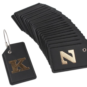Detail of black leather luggage tags with gold foil initials and steel wire loop cable