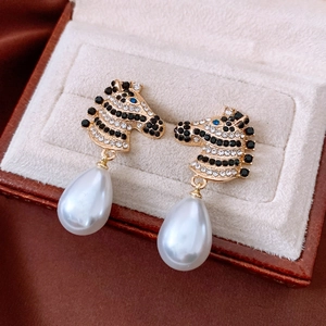 Detailed close-up of zebra horse head earrings with crystal inlay and drop pearl