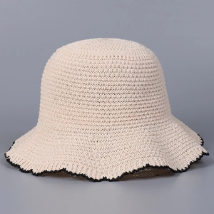 Detail of beige knit bucket hat featuring intricate mesh texture and black wavy edges