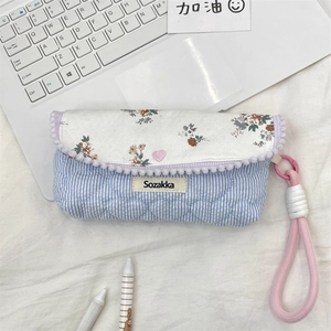 Detail of floral pencil case with heart button and pink rope handle on laptop keyboard