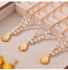 Detail of three gold shell pearl necklaces with small diamonds in a beige velvet box