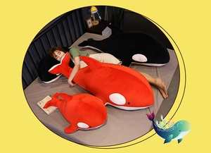 Detailed comparison of giant black and red orca plush toys in a cozy bedroom setting
