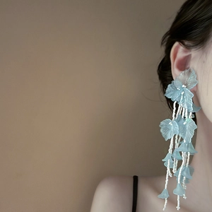 Eleganti orecchini a nappa con fiori blu indossati con lunghe catene di perline