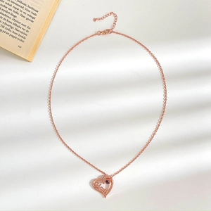 Macro detail of rose gold heart necklace featuring Mom lettering and a projection stone