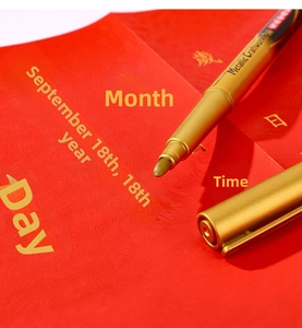 Close-up of golden metallic craft marker pen writing on textured red paper background