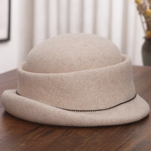 Detail of wool felt bowler hat with bead chain trim on dark wood surface