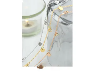 Detailed shot of gold, silver, and rose gold heart necklaces with zircon in warm setting