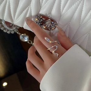 Detail of silver snake ring with cubic zirconia worn by model against a white handbag