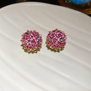 Macro detail of 3D pink rose flower stud earrings with sparkling rhinestones and gold base
