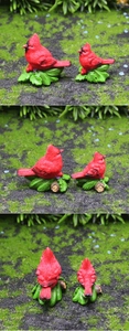 Three-sided view of decorative resin cardinal figurines on green moss and wooden base