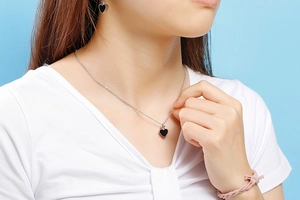 Gros plan d'un ensemble collier et boucles d'oreilles cœur noir sur un mannequin réel
