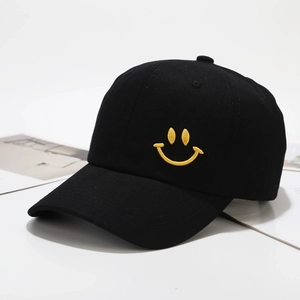 Detailopname van de gele smiley borduring op een zwarte katoenen honkbalpetje