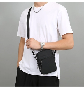 Men's black nylon cross-body bag with adjustable shoulder strap shown on a model