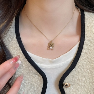 Model wearing a brown flocked bear pendant necklace with 18K gold bow and pearl detail