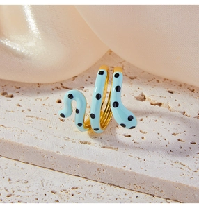 Macro detail of gold snake-shaped ring with light blue enamel and black polka dots