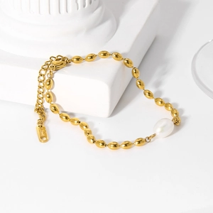 Detail of gold beads and white freshwater pearl bracelet on a white stone pedestal