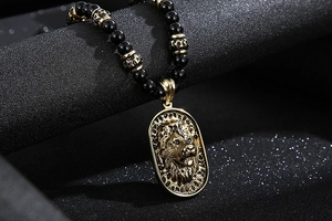 Detail of beaded necklace with embossed golden lion head pendant on black beads