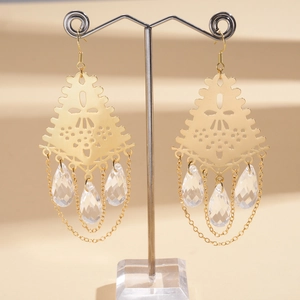 Détail de boucles d'oreilles dorées avec triangles ciselés et pampilles en verre cristal