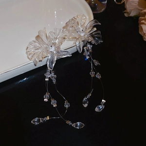 Macro detail of transparent flower earrings with long tassels on a black surface