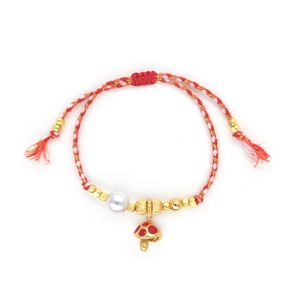 Close-up of handmade woven red cotton bracelet with gold beads and mushroom charm