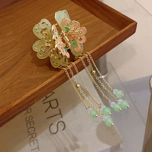 Detail of floral tassel hair claw clip with light green beads and golden petals