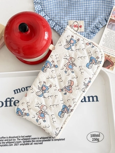 Close-up of quilted cream pouch with cartoon girl print and zipper closure on a tray