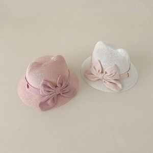 Close-up of baby straw sun hats with cat ears and large bows in pink and white