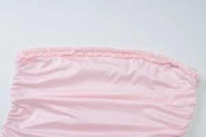 Close-up of pink satin fabric with ruffled edges and pleated texture on tiered dress