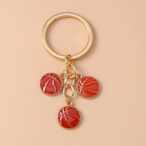 Detailed close-up of golden keychain featuring three red basketball enamel pendants