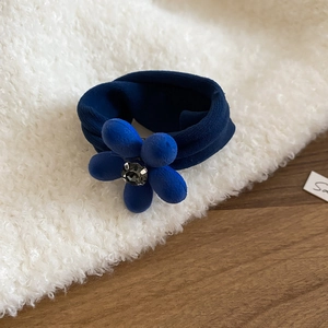 Gros plan du chouchou floral en velours bleu marine avec un centre en strass brillant
