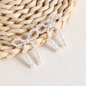 Detailed view of handmade pearl bow earrings with elegant dangling fringe tassels
