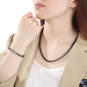 Close-up of vintage black titanium steel Cuban chain necklace and bracelet set on a model