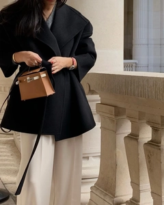 Detail shot of a brown leather mini handbag paired with a black wool coat for autumn
