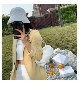 White cloud shoulder bag with chunky gold chain strap shown in an outdoor picnic setting