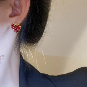 Close-up of a realistic red strawberry stud earring worn on a model's ear