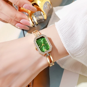Gros plan d'une montre à quartz dorée avec cadran émeraude et bracelet serti de diamants