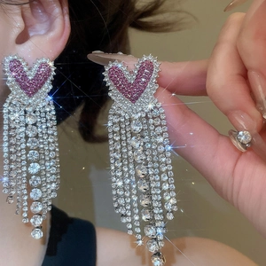 Detailed close-up of pink crystal heart earrings with shimmering silver tassel fringes