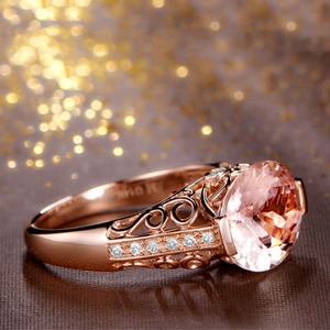 Detail of rose gold ring featuring a round pink gemstone and intricate hollow patterns