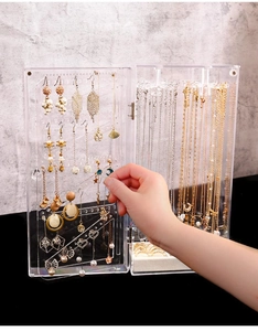 Close-up of a clear acrylic jewelry box with multi-hook sections for necklaces and earrings