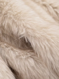 Gros plan sur la texture épaisse d'une fausse fourrure beige clair aux fibres douces