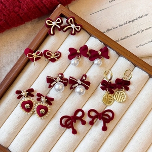 Macro shot of red flocked bow earrings with gold metal accents and pearl details