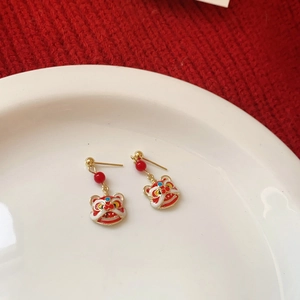 Detail of red festive lion dance tassel earrings on a white plate and red fabric