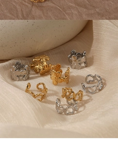 Detailed shot of hollow heart and flower earrings on elegant beige silk fabric