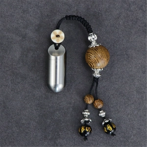 Close-up of portable titanium capsule with tiger eye wood bead and gold Sanskrit engraving