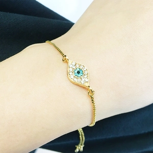 Close-up of a gold adjustable evil eye bracelet with blue rhinestones on a wrist