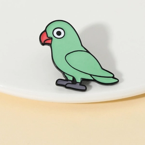 Détail macro d'une broche perroquet vert en émail avec finition brillante sur base métal