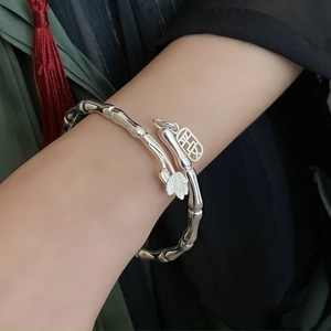 Detail of bamboo joint bracelet with lotus charm and engraved square pendant on wrist