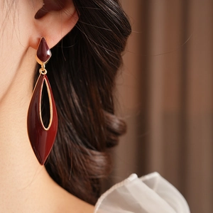 Detail of vintage red enamel teardrop earrings with gold rim worn by a model