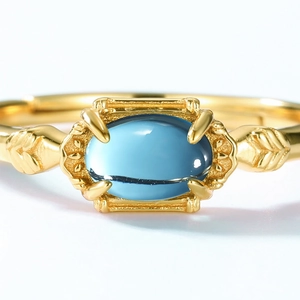 Macro view of blue oval gemstone ring with golden retro leaf carvings on the side
