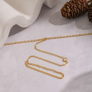 Elegante cavigliera a catena dorata con zircone scintillante su base di marmo